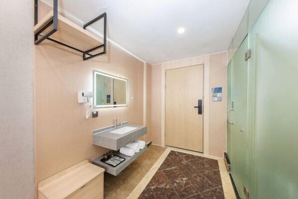 A modern bathroom with a large mirror, a built-in sink, a towel rack, and a shower area. - Oubosi Hotel (Qingyuan Gulongxia Qingxin Pedestrian Street) (Qingyuan)