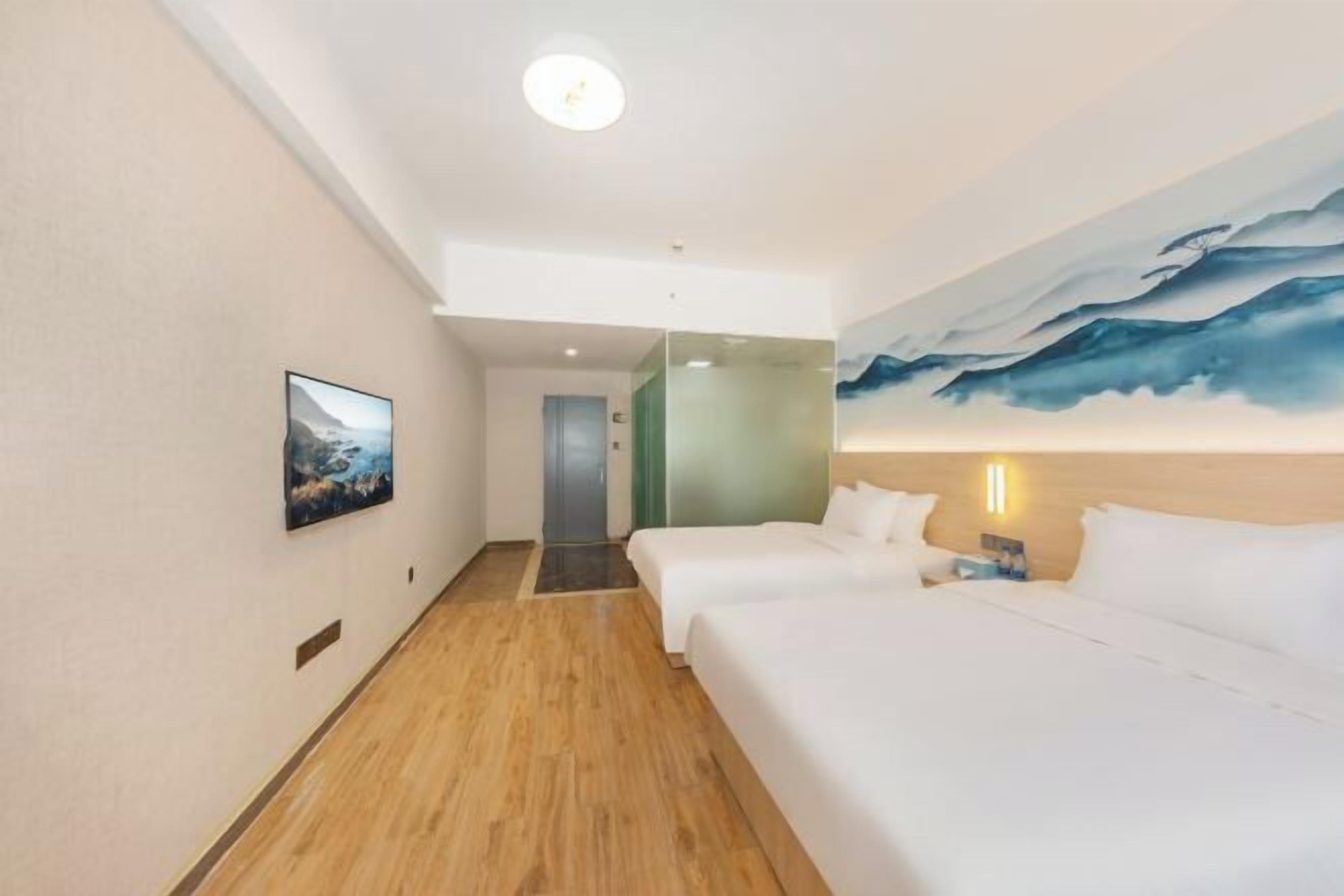 A hotel room with two beds, a painting on the wall, a television, and a wooden floor.
