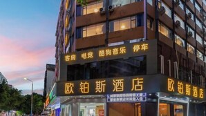Un hôtel à plusieurs étages, doté d’une enseigne lumineuse dans une langue étrangère.
