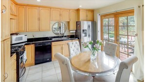 A kitchen with wooden cabinets, a stainless steel refrigerator, a microwave, and a dining table with chairs. - Sunny San Diego La Mesa Charming 2 bd /1 bth Home, Beaches, Sea World, Zoo, (La Mesa)