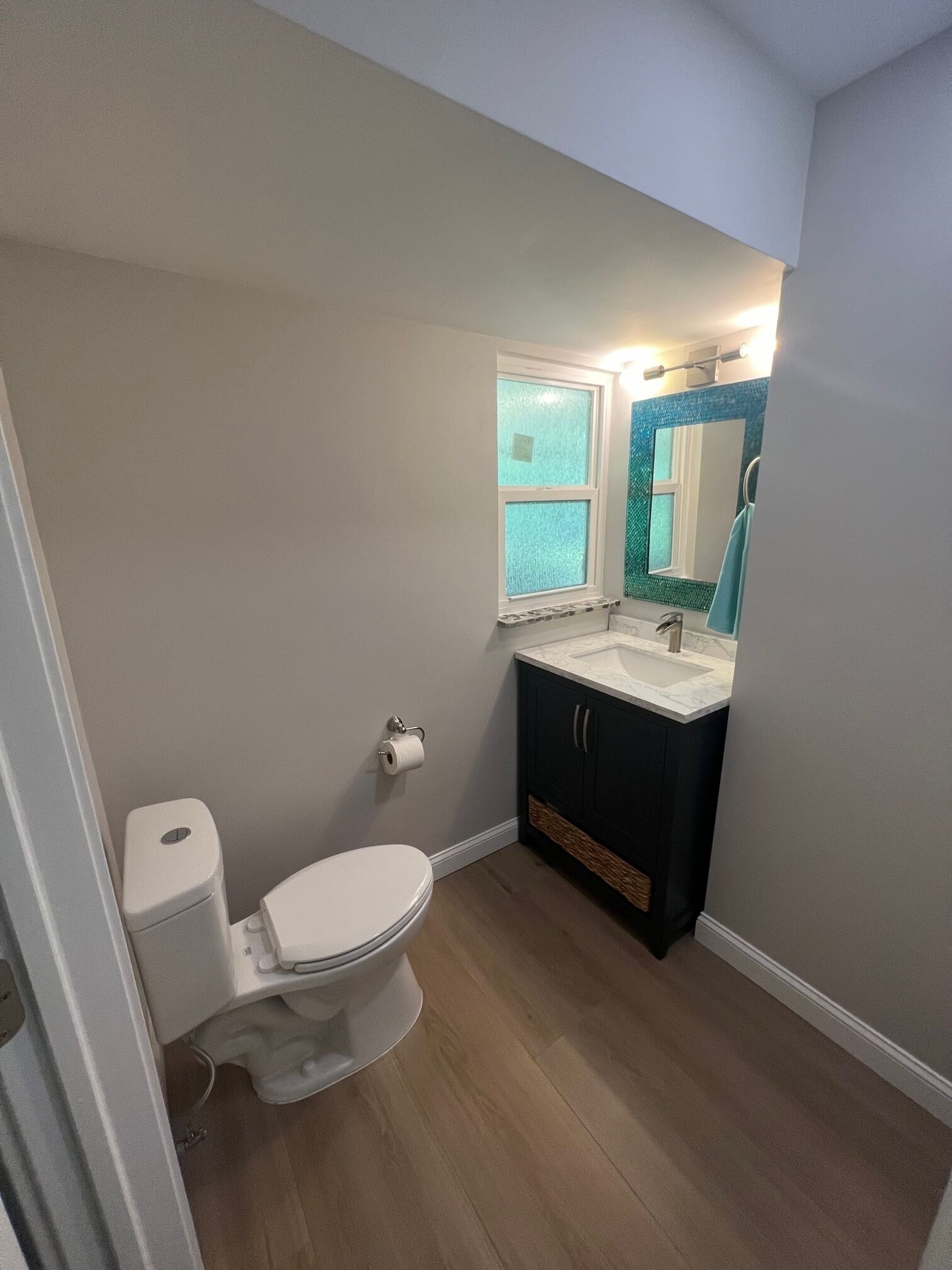 A compact bathroom with a toilet, sink, and mirror.