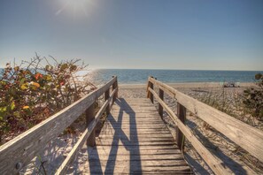 A wooden boardwalk leading to a beach with clear skies.