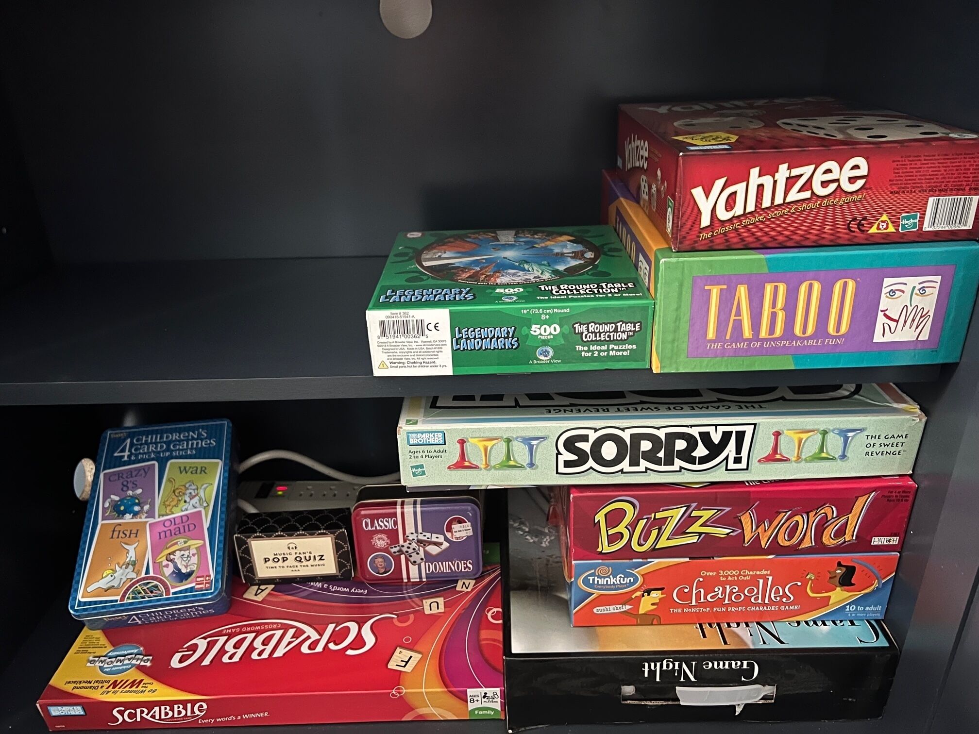 A shelf with various board games, including 'Scrabble', 'Sorry!', 'Buzzword', and 'Taboo'.