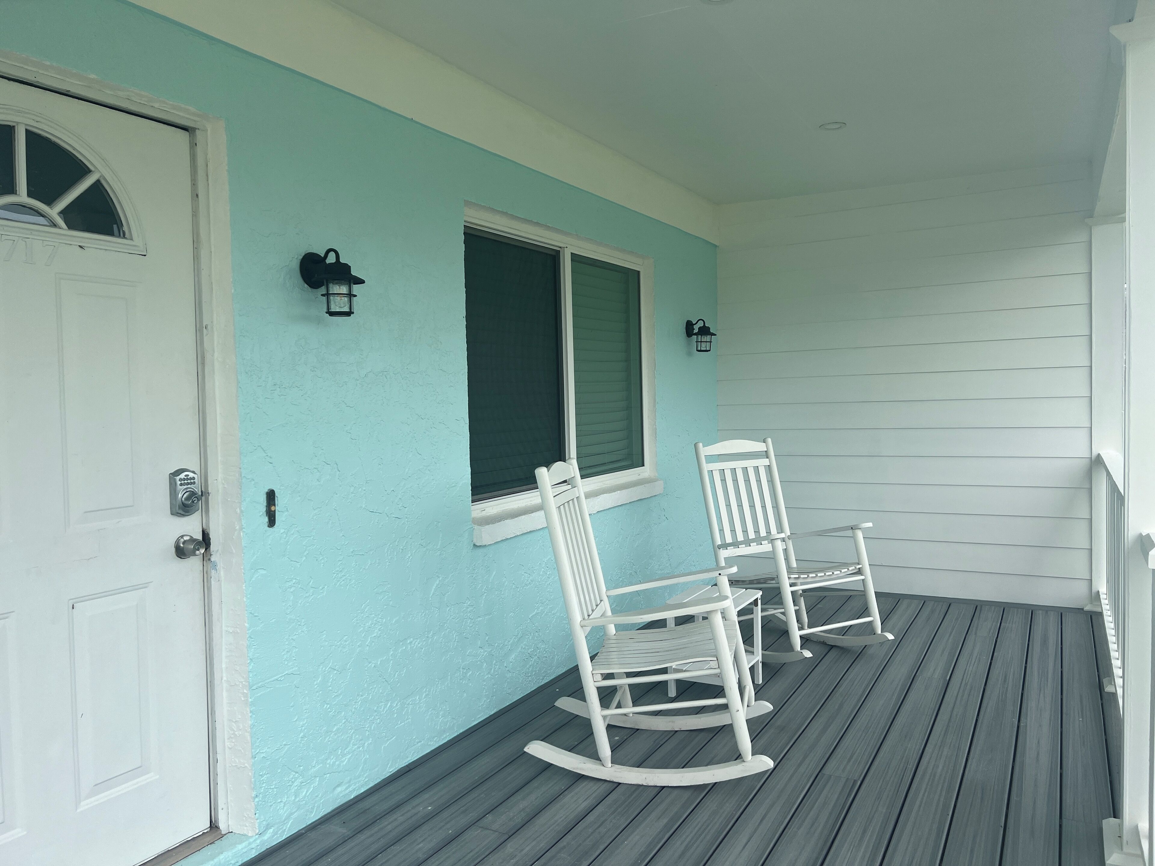 A porch with two rocking chairs and a door.