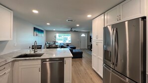 A modern kitchen with white cabinets, stainless steel appliances, and a central island. - Blue Water Retreat @ Vanderbilt- steps to beaches/shopping/dining/entertainment! (Naples)