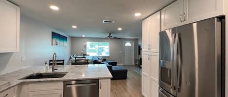 A modern kitchen with white cabinets, stainless steel appliances, and a central island.
