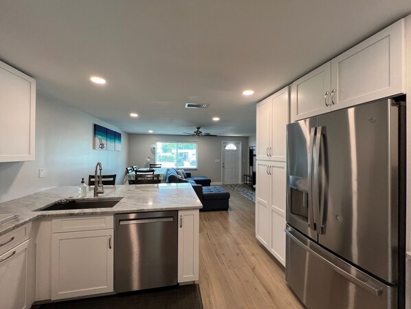 A modern kitchen with white cabinets, stainless steel appliances, and a central island.