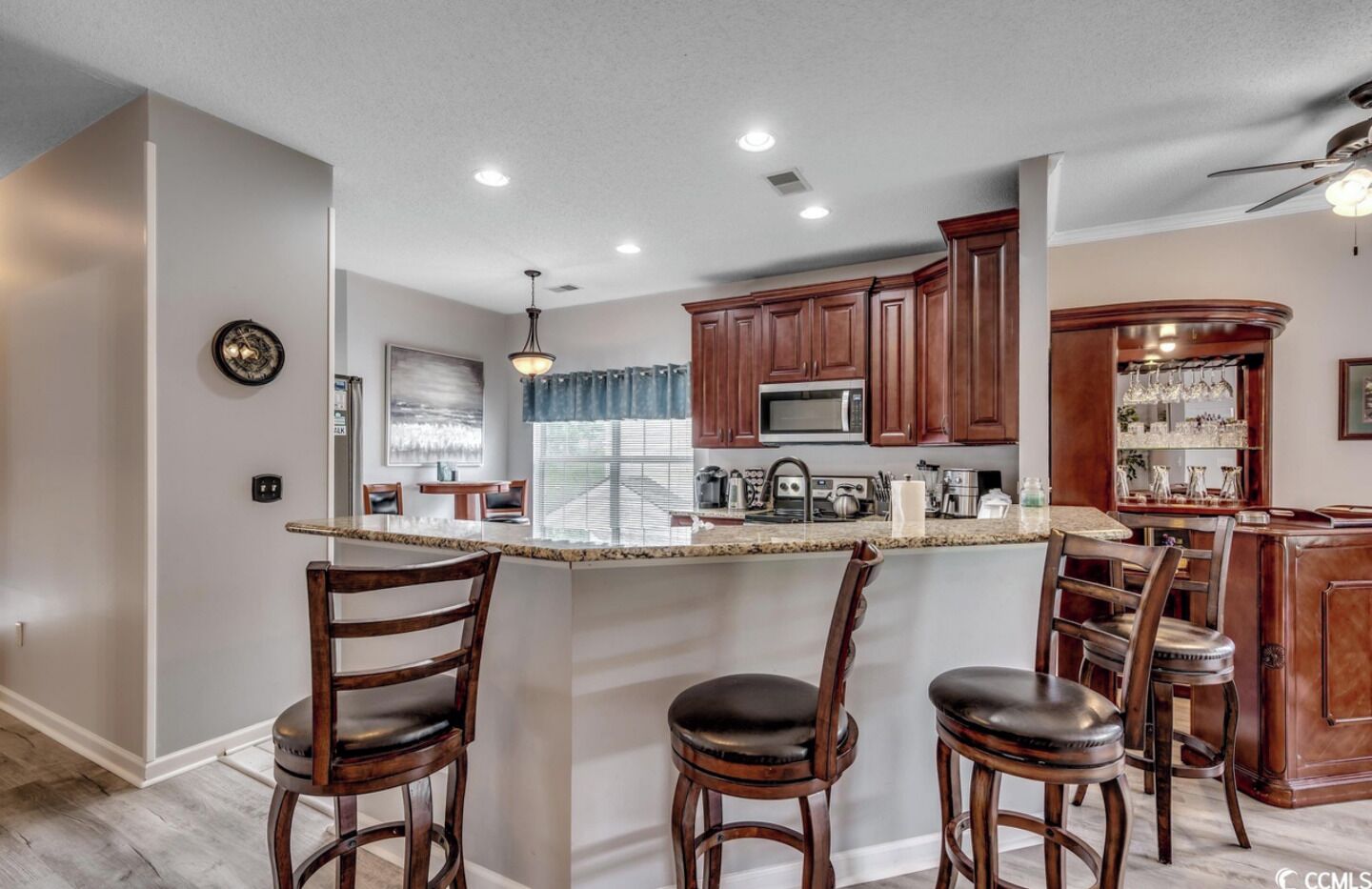 A modern kitchen with a central island, wooden bar stools, and built-in appliances.