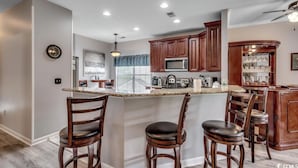 A modern kitchen with a central island, wooden bar stools, and built-in appliances. - Myrtle Beach Legends Golf Condo, on course! 3BR/2BA, pool, hot tub, and tennis. (Myrtle Beach)