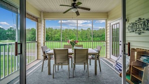 A covered patio with a table and chairs, a ceiling fan, and a view of a green landscape. - Myrtle Beach Legends Golf Condo, on course! 3BR/2BA, pool, hot tub, and tennis. (Myrtle Beach)