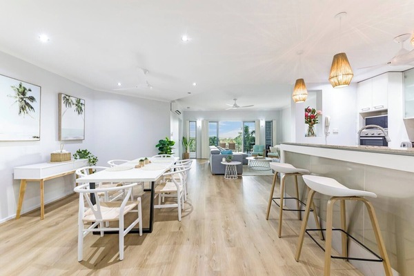 A modern, open kitchen features an island bench with a breakfast bar for casual dining