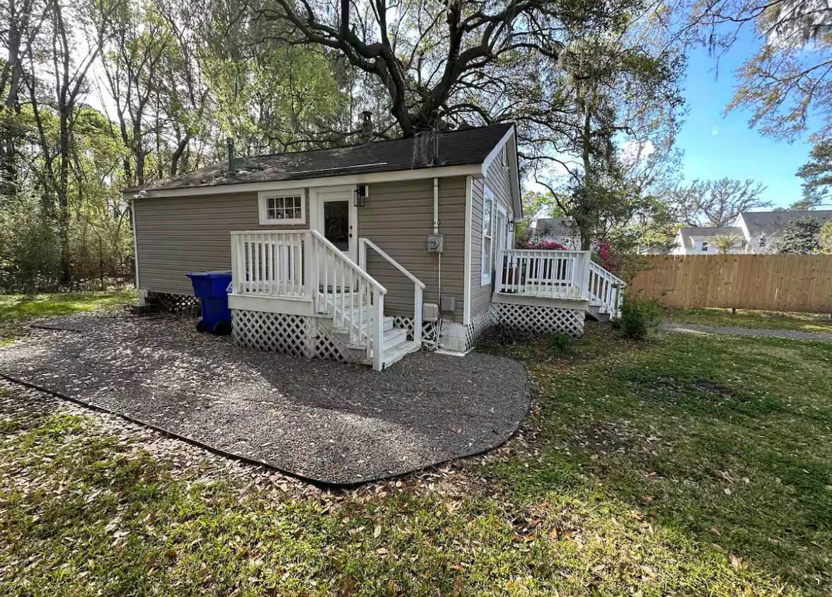 A small, single-story house with a front porch and a covered patio area.