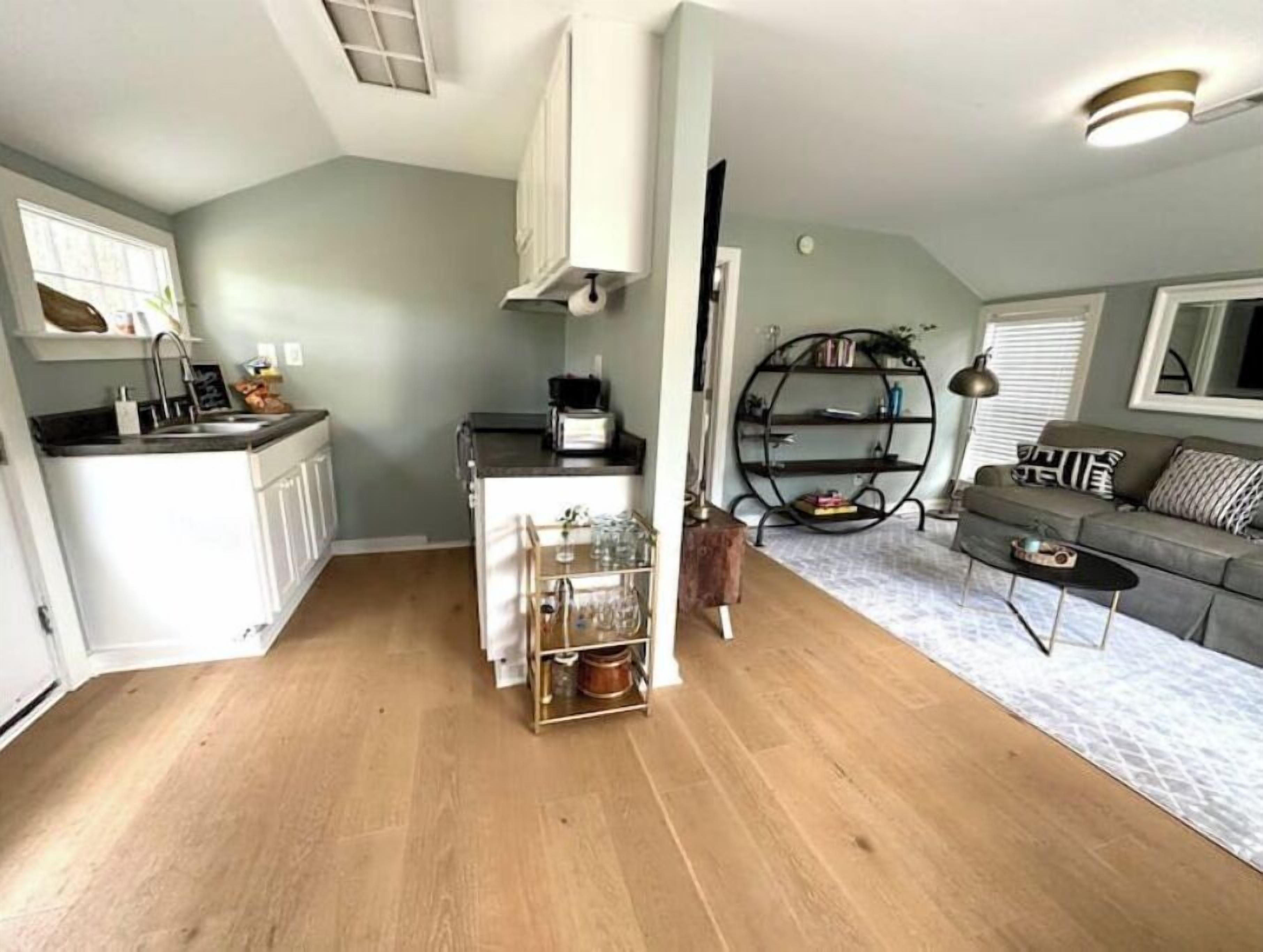 Un espacio habitable compacto con kitchenette, comedor y sala de estar con sofá y mesa de centro.