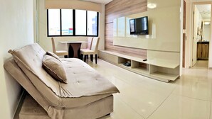 Una sala de estar moderna con un sofá, un televisor montado en la pared y un comedor.