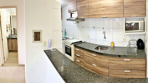 Una cocina moderna con armarios de madera, un lavamanos de acero inoxidable, un microondas y un horno empotrado.