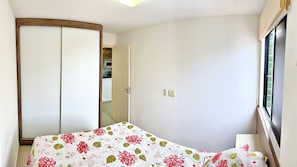A bedroom with a bed, a wardrobe, a window, and a door leading to a bathroom.