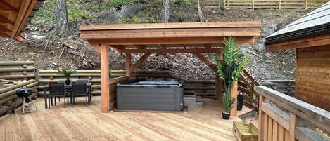 Une terrasse en bois avec un jacuzzi, des sièges d’extérieur et une pergola.