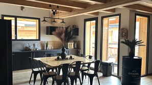 A modern kitchen with wooden cabinets, a dining area with a large table and chairs, and a unique ceiling fan design.