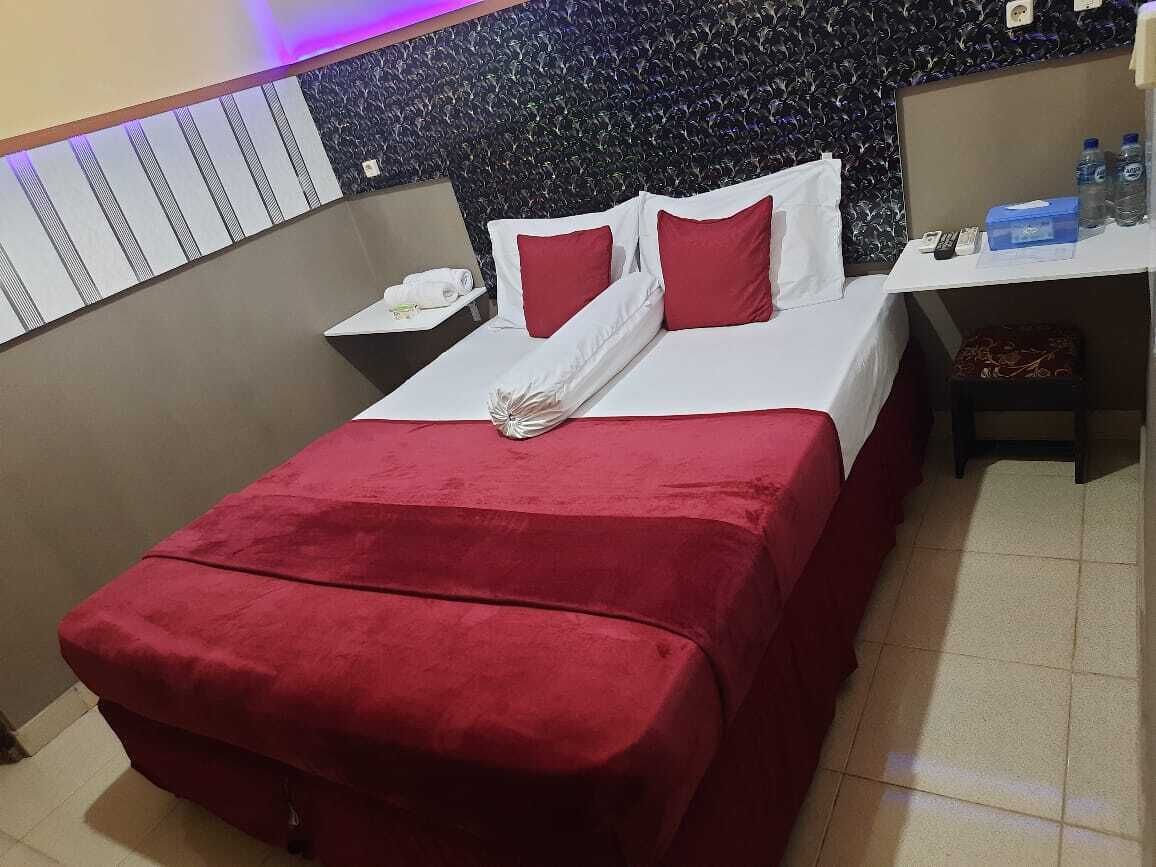 Habitación de hotel con cama, almohadas, mesita de noche, escritorio y una silla.