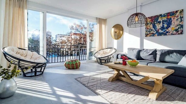 A modern living room with a sofa, two chairs, a coffee table, and a large window with a view of buildings and trees. - Beachclose apt Marbella by Costarentals - M28 (Marbella)