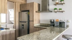 A modern kitchen with a stainless steel refrigerator, a built-in oven, a microwave, and a coffee maker.