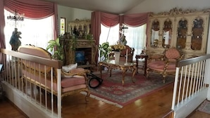 Un salon traditionnel avec une cheminée, des meubles richement décorés et un escalier.