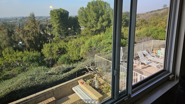Un balcon offrant une vue sur le paysage urbain et la verdure.