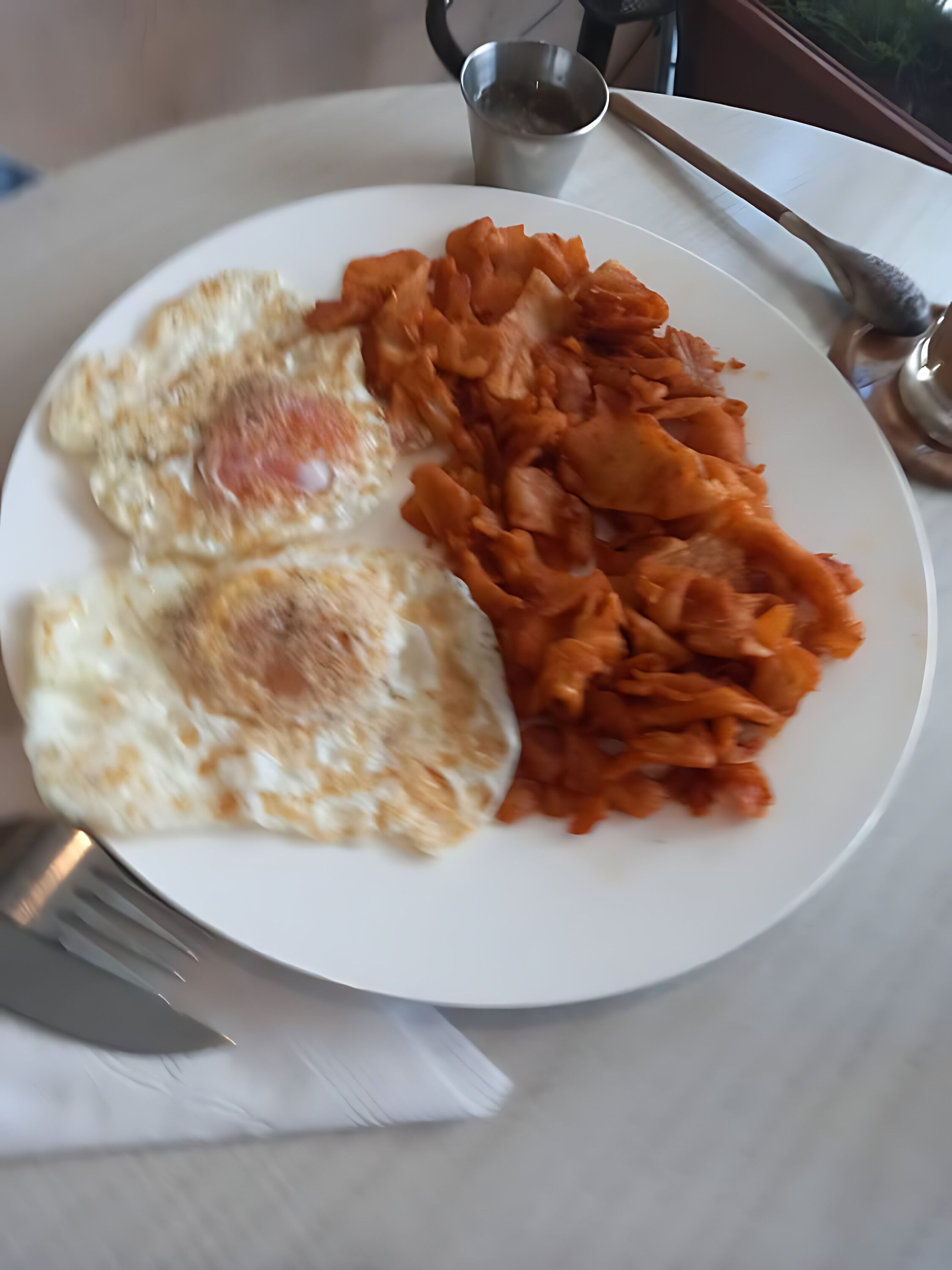 Un plato con dos huevos fritos y una porción de kimchi.