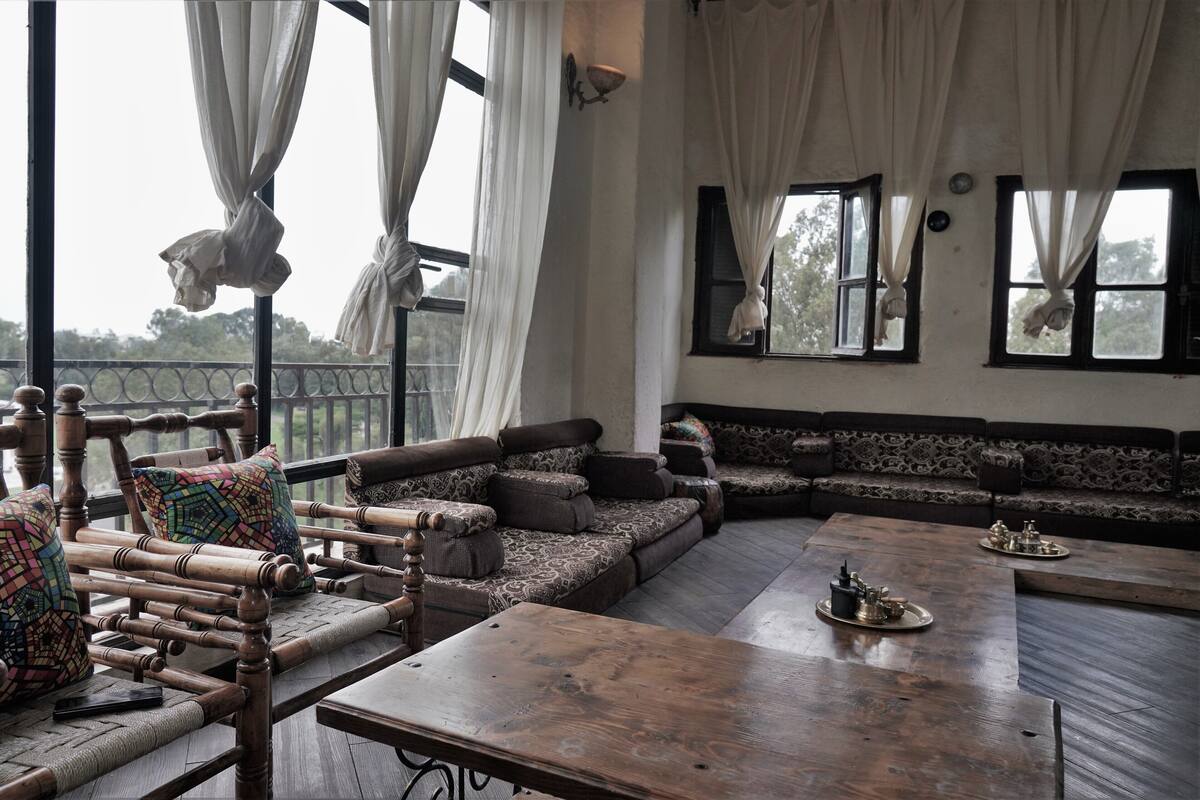 A spacious room with a large wooden table, a sofa set, and a balcony with curtains.