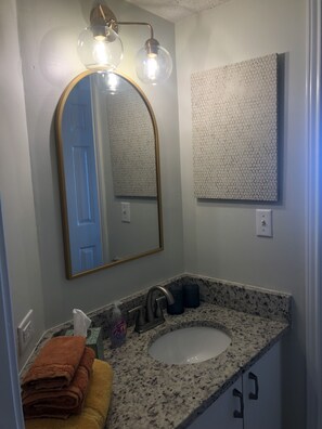 A bathroom with a round mirror, a sink, and a towel rack. - THE BEACH IS OPEN ALL YEAR!
Start Planning Your Fall and Winter Vacation Today! (Gulf Shores)