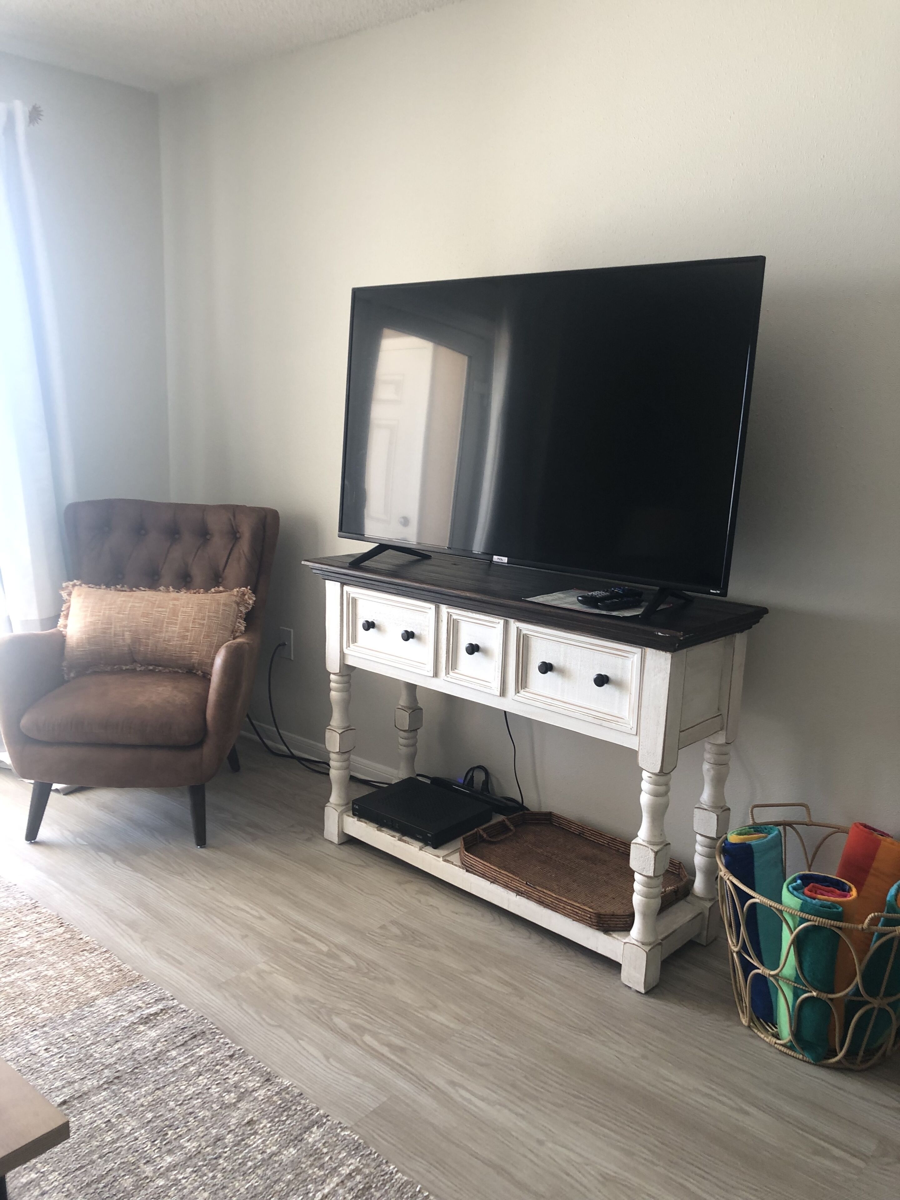 Habitació amb un envellidor blanc, un armari marró i un televisor a la part superior.