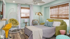 Quarto com cama, uma cadeira, uma mesa e um ventilador de teto.
