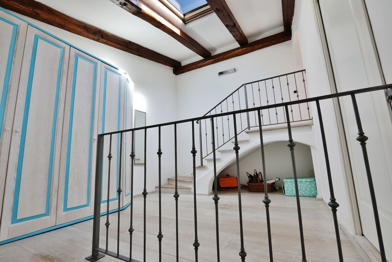 Una escalera con barandilla de metal negro que conduce a un piso superior.