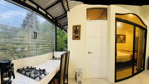 Een compacte hotelkamer met een kitchenette, een schuifdeur naar een slaapkamer en uitzicht door een raam.