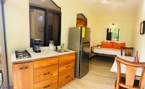 A compact kitchen with a gas stove, coffee maker, and a refrigerator. - Enchanted Sloth (Manuel Antonio)