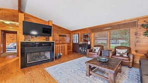 A log cabin interior with a fireplace, leather furniture, and wooden walls.