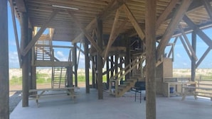 A wooden structure with a concrete floor, benches, and a staircase leading to an upper level.
