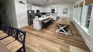 A modern kitchen with white cabinets, a central island, and a dining area with wooden chairs.