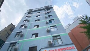 A multi-story building with air conditioning units on the exterior, a visible logo, and a sign with Chinese characters. - Afuer Chain Smart Hotel (Weixin Lianyi Branch) (Weixin)