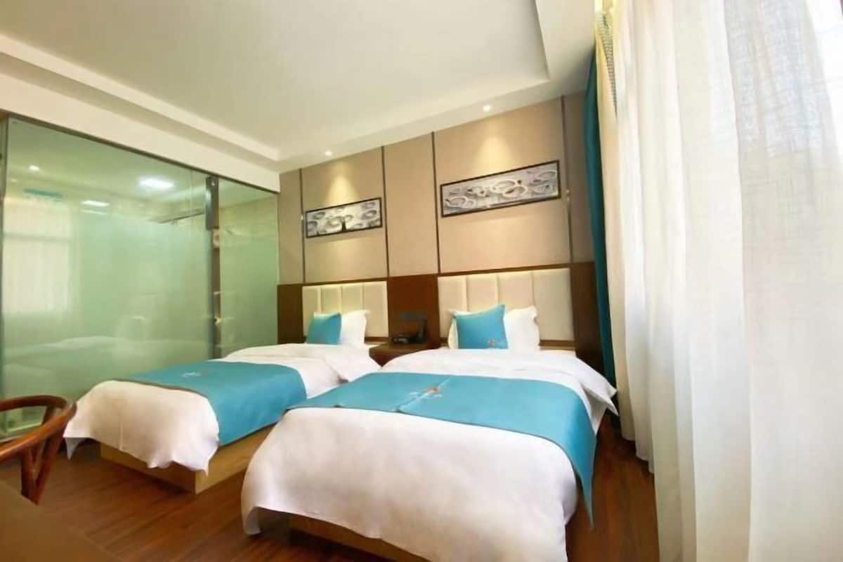 Ein Hotelzimmer mit zwei Betten, einer Duschkabine aus Glas und einem modernen Design.