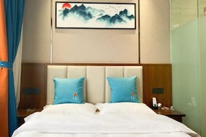 A hotel room with a bed, two pillows, a nightstand, a phone, and a painting on the wall.