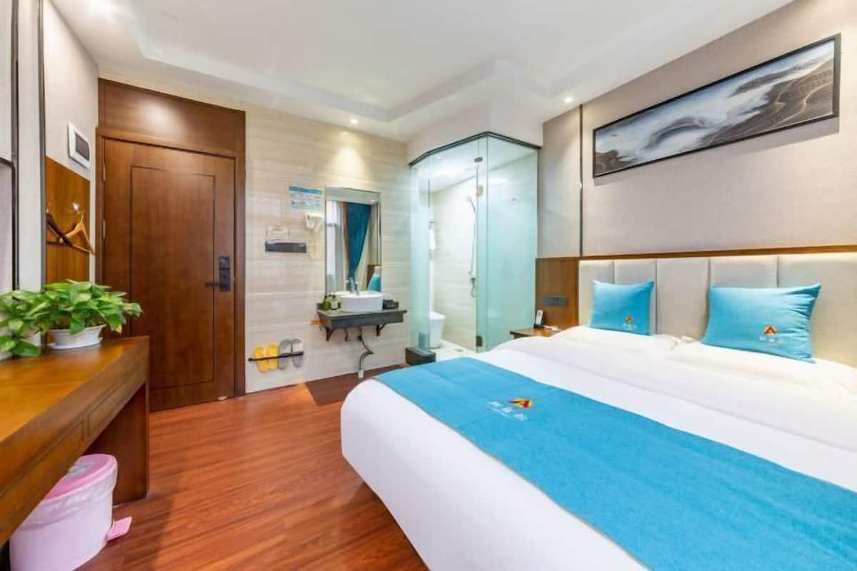 Ein Hotelzimmer mit einem Bett, einem Holztisch, einem Badezimmer und einem Bild an der Wand.