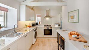 Une cuisine compacte avec des meubles blancs, un four à micro-ondes, une cuisinière à gaz et un évier.
