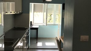 Una cocina moderna con una isla central, un comedor con mesa y sillas, y un ventanal que proporciona luz natural.