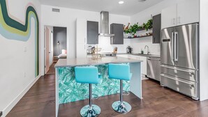 A modern kitchen with a central island, stainless steel appliances, and a vibrant backsplash. - Jungle House: 2 Bed Condo w/parking & Patio (Denver)