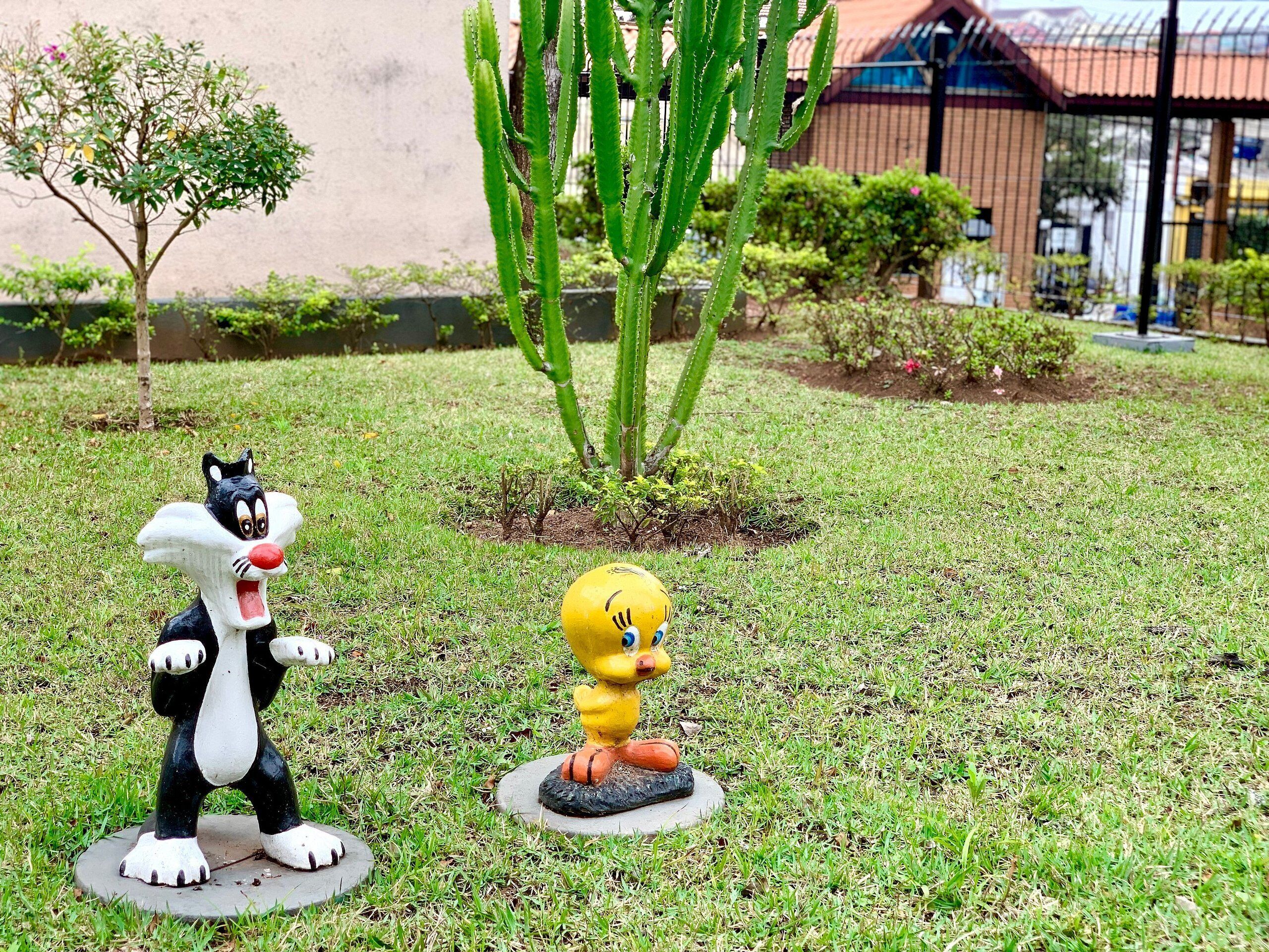 Un jardin avec un cactus et deux statues de personnages de dessins animés, le tout posé sur une base circulaire.