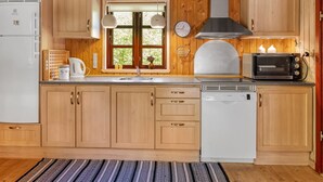 A kitchen with wooden cabinets, a sink, a Bosch dishwasher, a Bosch microwave, and a window with a view of greenery.