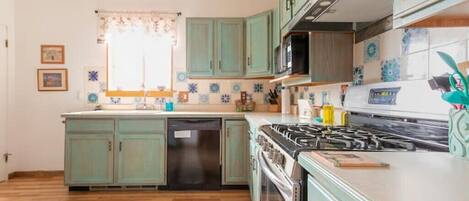 Una cocina con gabinetes color turquesa, una estufa y un lavavajillas.