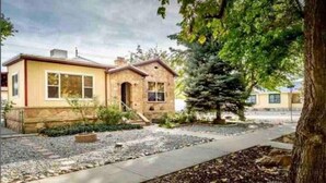 A single-story house with a stone facade, a front porch, and a small front yard with a tree and gravel path.