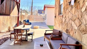 A covered patio with a table, chairs, and a sofa.